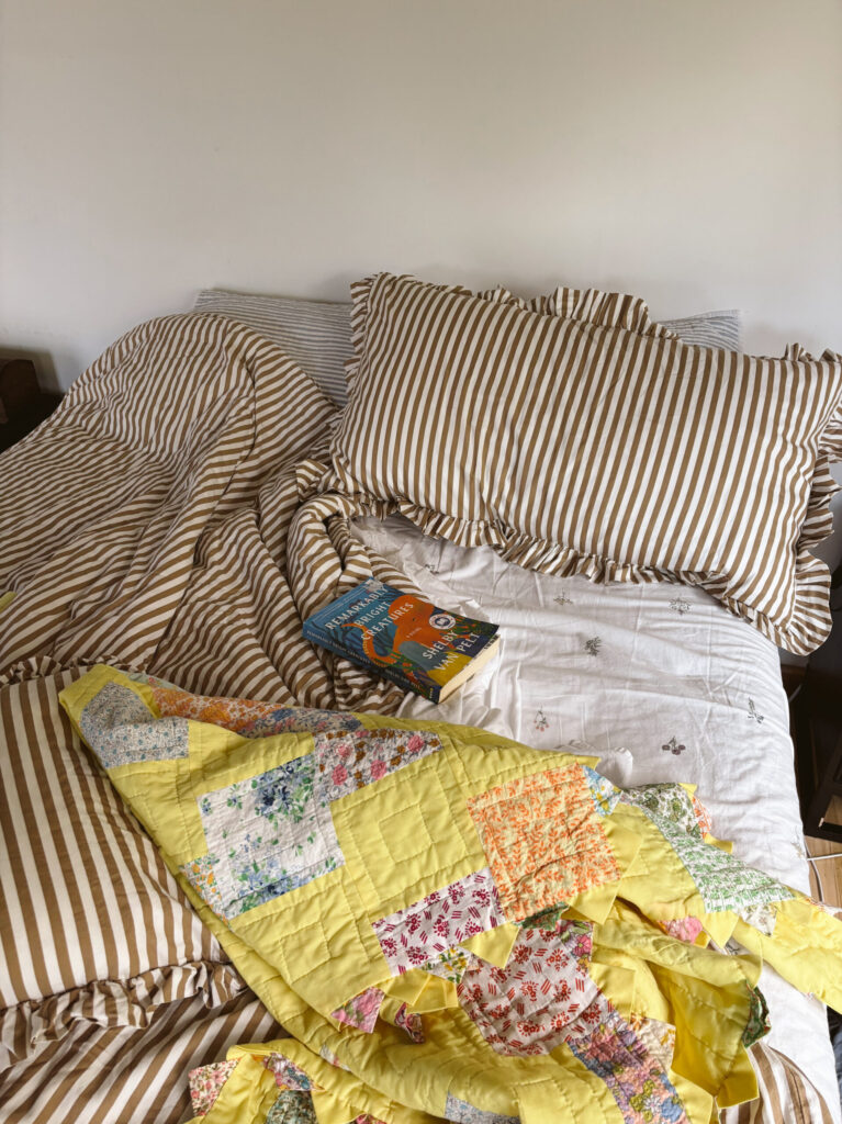 unmade bed with yellow quilt
